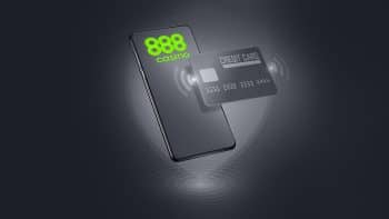 mobile smartphone with the 888 casino logo with a credit card hovering over it on a grey and black background
