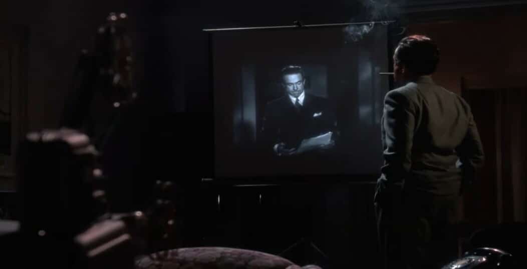 Bugsy casino movie scene with the character Bugsy watching a black and white movie and smoking a cigar