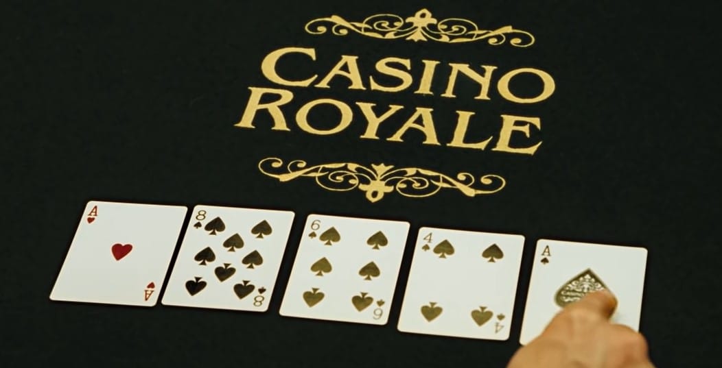Casino Royale movie scene with poker cards being placed on the table with a golden Casino Royale inscription