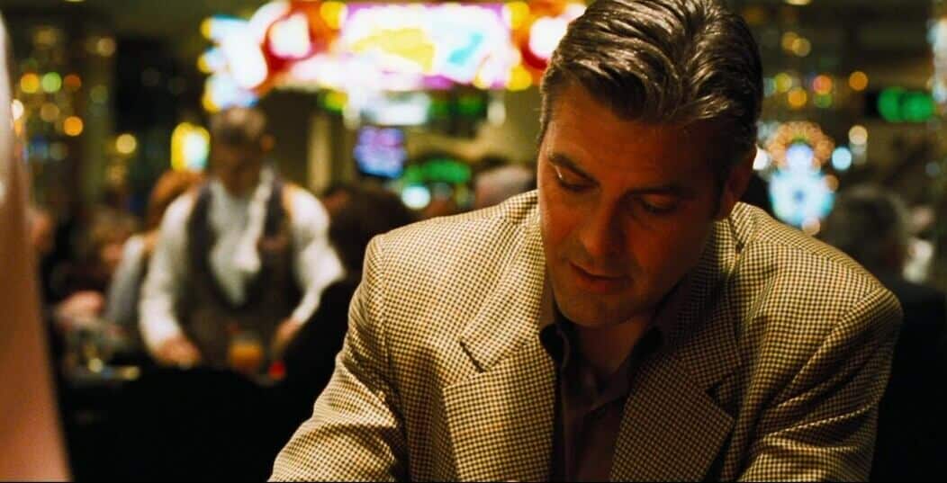 Ocean Eleven casino movie scene with actor George Clooney sitting at a casino table looking down