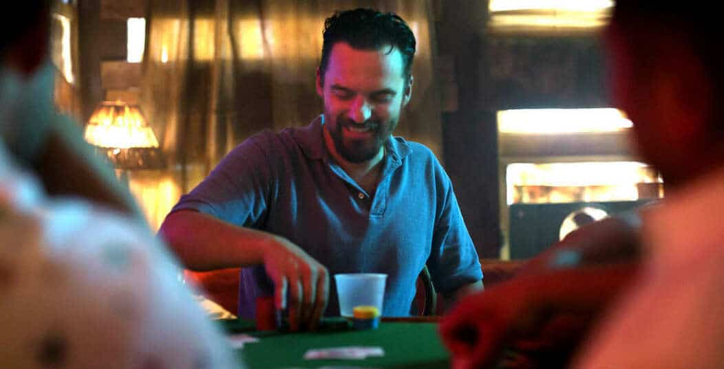 Win it all casino movie scene with the main character sitting at a poker table and holding a pile of poker chips with one hand